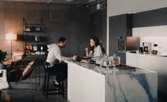 a man and woman sitting at a kitchen counter talking to each other in the living room