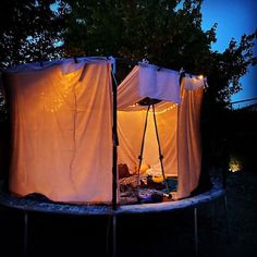 an outdoor tent is lit up at night with the lights on and curtains pulled down