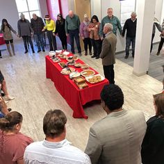 a group of people standing in front of a table with food on top of it