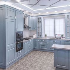 a large kitchen with blue cabinets and white counter tops, an island in the middle