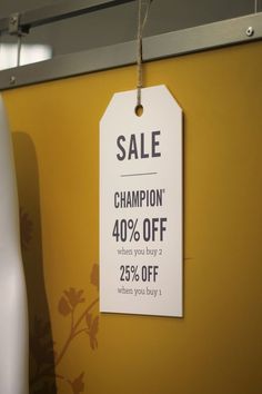 a sale sign hanging from the side of a yellow wall