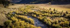 an aerial view of a river running through a valley with mountains in the back ground