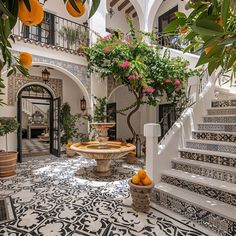 an indoor courtyard with oranges and potted plants on the steps leading up to it