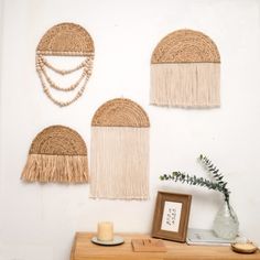 three woven wall hangings on a white wall next to a vase with a candle