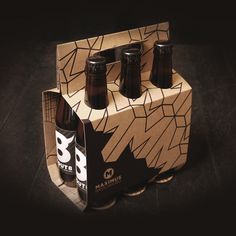 four beer bottles in a cardboard box on a black surface with the bottom half open