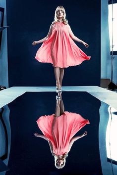 a woman in a pink dress is reflected in the water