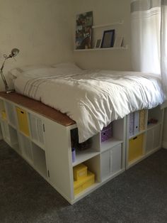 a bed sitting on top of a white shelf next to a window