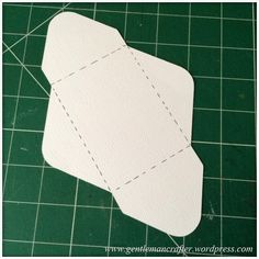 a piece of white paper cut out to look like an origami plane on a green cutting mat