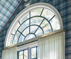 an arched window in a blue and white room with plaid curtains on the windowsill