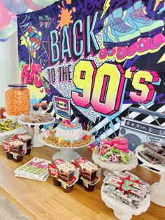 an assortment of desserts and snacks on a table in front of a wall with the words back to the 90's