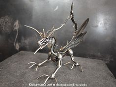 a small metal insect sitting on top of a stone slab in front of a black wall