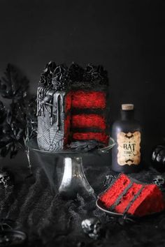 a red cake sitting on top of a table next to a bottle