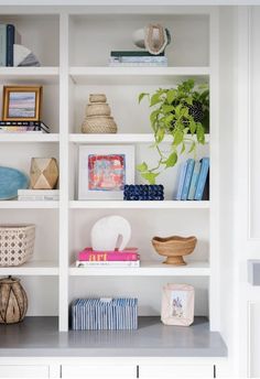 a white book shelf filled with lots of books and vases on top of it