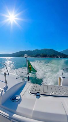 the sun shines brightly on a boat traveling through the open water with mountains in the background