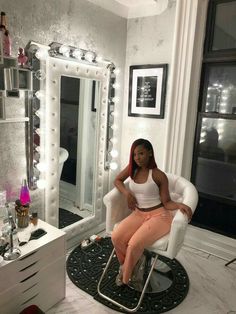 a woman sitting on a chair in front of a mirror with lights around her head