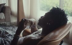 a man laying on top of a couch next to a window