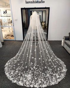 a white wedding veil with flowers on the bottom is hanging in front of a doorway