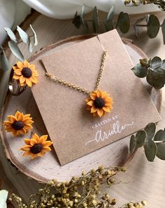 the sunflower necklace is on display next to some flowers