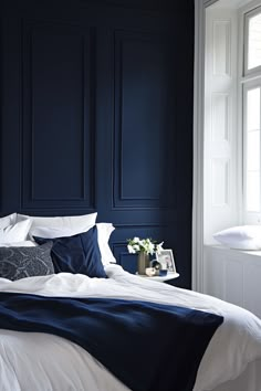 a bedroom with dark blue walls and white bedding