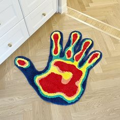 a colorful hand rug is on the floor next to a white cabinet and drawers in a room