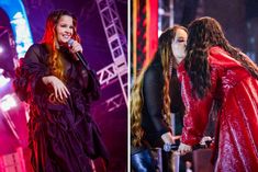 two women in red and black outfits on stage one is holding a microphone while the other has long hair