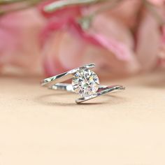 a diamond ring sitting on top of a pink flower