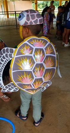 a little boy wearing a costume made to look like a turtle with wings and flowers on it's back