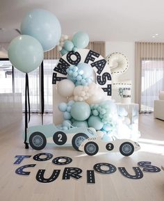 a birthday cake with balloons and cars on the floor in front of it that says congratulations