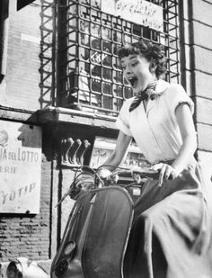 a black and white photo of a woman on a scooter