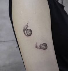 a woman's arm with two small snails on the back of her left arm