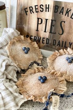 three pies with blueberries on them sitting next to a sign