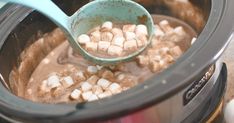 a spoon full of marshmallows is being stirred in the slow cooker