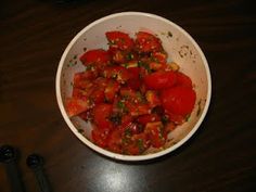 a white bowl filled with sliced tomatoes on top of a wooden table