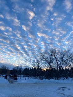 the sky is covered with clouds and snow as it sits in front of some trees