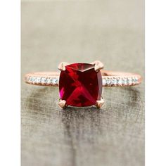 an engagement ring with a red stone surrounded by diamonds