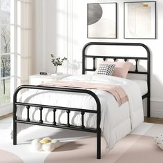 a black metal bed frame in a white room with pink carpet and pictures on the wall