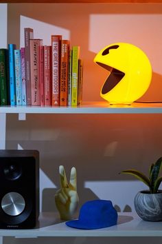 a book shelf with books, speakers and a yellow light on it's side