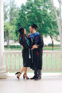 a man and woman in graduation gowns hugging each other