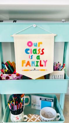 a blue cart filled with craft supplies and a banner that says our class is a family