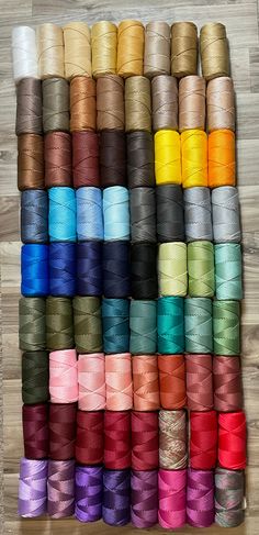 many spools of different colors of thread on a wooden surface with wood flooring