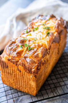 a loaf of bread with cheese and sauce on it sitting on a cooling rack next to a napkin