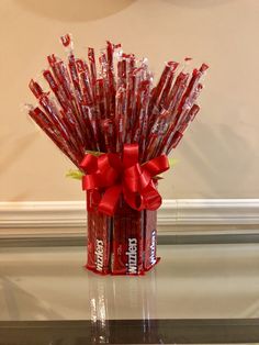 a red vase filled with candy canes on top of a table