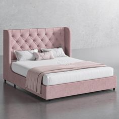 a pink bed with white sheets and pillows on top of it, in front of a gray wall