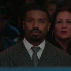 a man wearing a suit and tie in front of an audience at a sporting event