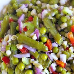 a white bowl filled with peas, carrots and other vegetables on top of a table