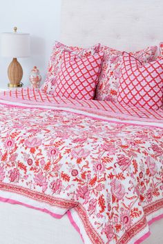 a bed with pink and white bedspread and pillows