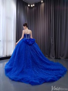 a woman in a blue ball gown is looking out the window