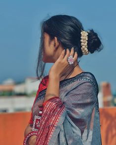 a woman in a sari is talking on her cell phone while wearing a pair of earrings