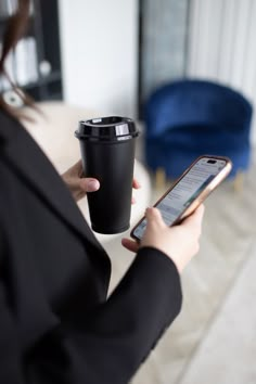 a woman holding a cup and cell phone