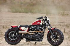 a red and white motorcycle parked on top of a dirt field